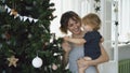 Happy mother and her little daughter playing near the Christmas tree at home Royalty Free Stock Photo