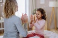 Happy mother with her little daughte playing clapping hands game on bed at home.