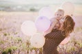 Happy mother and her little son posing with colorful balloons in a lavender field Royalty Free Stock Photo