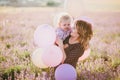 Happy mother and her little son posing with colorful balloons in a lavender field Royalty Free Stock Photo