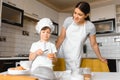 Happy mother and her little son shaking raw eggs in bowl before making dough for homemade pastry in the kitchen Royalty Free Stock Photo