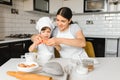 Happy mother and her little son shaking raw eggs in bowl before making dough for homemade pastry in the kitchen Royalty Free Stock Photo