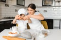 Happy mother and her little son shaking raw eggs in bowl before making dough for homemade pastry in the kitchen Royalty Free Stock Photo