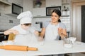 A young and beautiful mom is preparing food at home in the kitchen, along with her little son Royalty Free Stock Photo