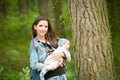 Happy mother with her newborn baby outdoors. young and stylish mother with long hair and a jeans jacket playing with her little Royalty Free Stock Photo