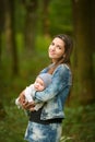 Happy mother with her newborn baby outdoors. young and stylish mother with long hair and a jeans jacket playing with her little Royalty Free Stock Photo