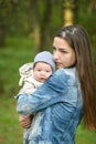 Happy mother with her newborn baby outdoors. young and stylish mother with long hair and a jeans jacket playing with her little Royalty Free Stock Photo