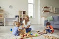 Happy mother and her two children at home, playing with lots of wood blocks, building big toy city Royalty Free Stock Photo