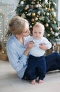 Happy mother with her young son on Christmas Eve near the Christmas tree Royalty Free Stock Photo