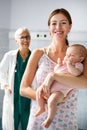 Mother holding adorable baby with smiling pediatrician doctor in hospital