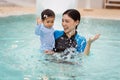 happy mother holding baby in her arms while playing water splashing in swimming pool