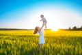 Happy mother holding baby smiling on wheat field in sunlight. Royalty Free Stock Photo