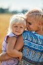 Happy mother holding baby smiling on a wheat field in sunlight Royalty Free Stock Photo