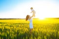 Happy mother holding baby smiling on wheat field in sunlight. Royalty Free Stock Photo