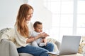 Happy mother holding cute baby daughter looking at laptop computer at home. Royalty Free Stock Photo