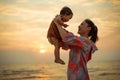 happy mother holding and lifting with toddler baby girl on the sea beach at sunset Royalty Free Stock Photo