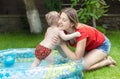 Happy young mother hugging her baby son swimming in inflatable pool at backyard Royalty Free Stock Photo