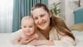 Happy mother hugging her smiling little baby while lying with him in bed. Concept of parenting ,baby care and family Royalty Free Stock Photo