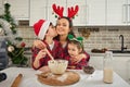 Happy mother hugs her adorable kids, all dressed in red and green plaid clothes. Cute son, young teenager kissing mom on cheek