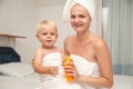 Happy mother and infant baby in white towels after bathing apply sunscreen or after sun lotion or cream. Children skin care. Spf,