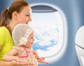 Happy mother and kid sitting near airplane window