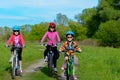 Happy mother and kids on bikes cycling outdoors