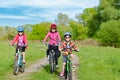 Happy mother and kids on bikes cycling outdoors in park, active family sport and fitness