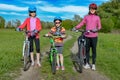 Happy mother and kids on bikes cycling outdoors in park, active family sport