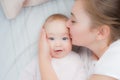 Happy mother kisses baby lying on the bed. Top view Royalty Free Stock Photo