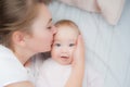 Happy mother kisses baby lying on the bed. Top view Royalty Free Stock Photo