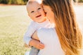 Happy mother kisses and hugs her baby in the park on a summer sunny day Royalty Free Stock Photo