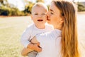 Happy mother kisses and hugs her baby in the park on a summer sunny day Royalty Free Stock Photo