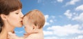 Happy mother kissing baby boy over sky background Royalty Free Stock Photo