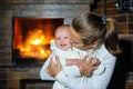 Happy mother kissing baby girl by the fireplace Royalty Free Stock Photo