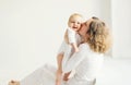 Happy mother kissing baby at home in white room Royalty Free Stock Photo