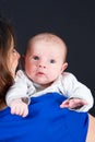 Happy mother kissing baby son at home on shoulder in arms Royalty Free Stock Photo