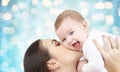 Happy mother kissing her baby over blue lights Royalty Free Stock Photo
