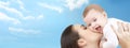 Happy mother kissing her baby over blue sky Royalty Free Stock Photo