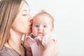 Happy mother kissing her baby at white background