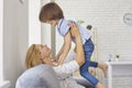 Happy mother lifting her son up into air at home. Parent playing game with little child, having fun in living room Royalty Free Stock Photo