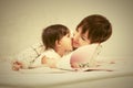 Happy mother and little baby girl reading a book on bed