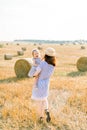 Happy mother and little baby girl standing next to hay bales in harvested field in sunny summer day. Mother and daughter Royalty Free Stock Photo