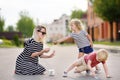 Happy mother and her little boy and girl drawing with colored chalk on asphalt Royalty Free Stock Photo