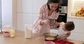 happy mother and little child girl sieving flour into bowl.