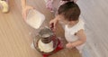 happy mother and little child girl sieving flour into bowl.