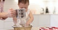 happy mother and little child girl sieving flour into bowl.