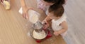 happy mother and little child girl sieving flour into bowl.