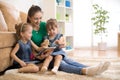 Happy mother and little daughters reading a book together in the living room at home. Family activity concept. Royalty Free Stock Photo