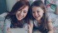 Happy mother and little girl taking selfie photo with smartphone camera and have fun grimacing while sitting in cozy bed Royalty Free Stock Photo