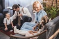 happy mother looking at cute little daughter sitting on sofa while father with son playing dominoes at home Royalty Free Stock Photo